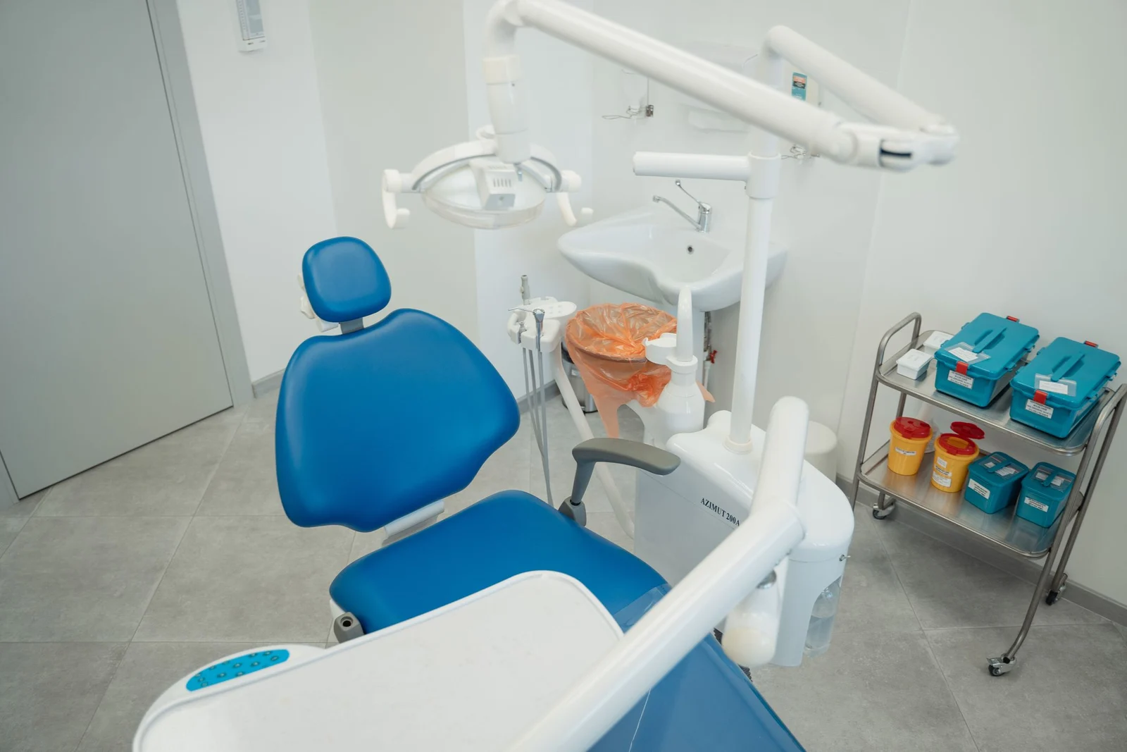 A bright treatment room with a blue chair and overhead light