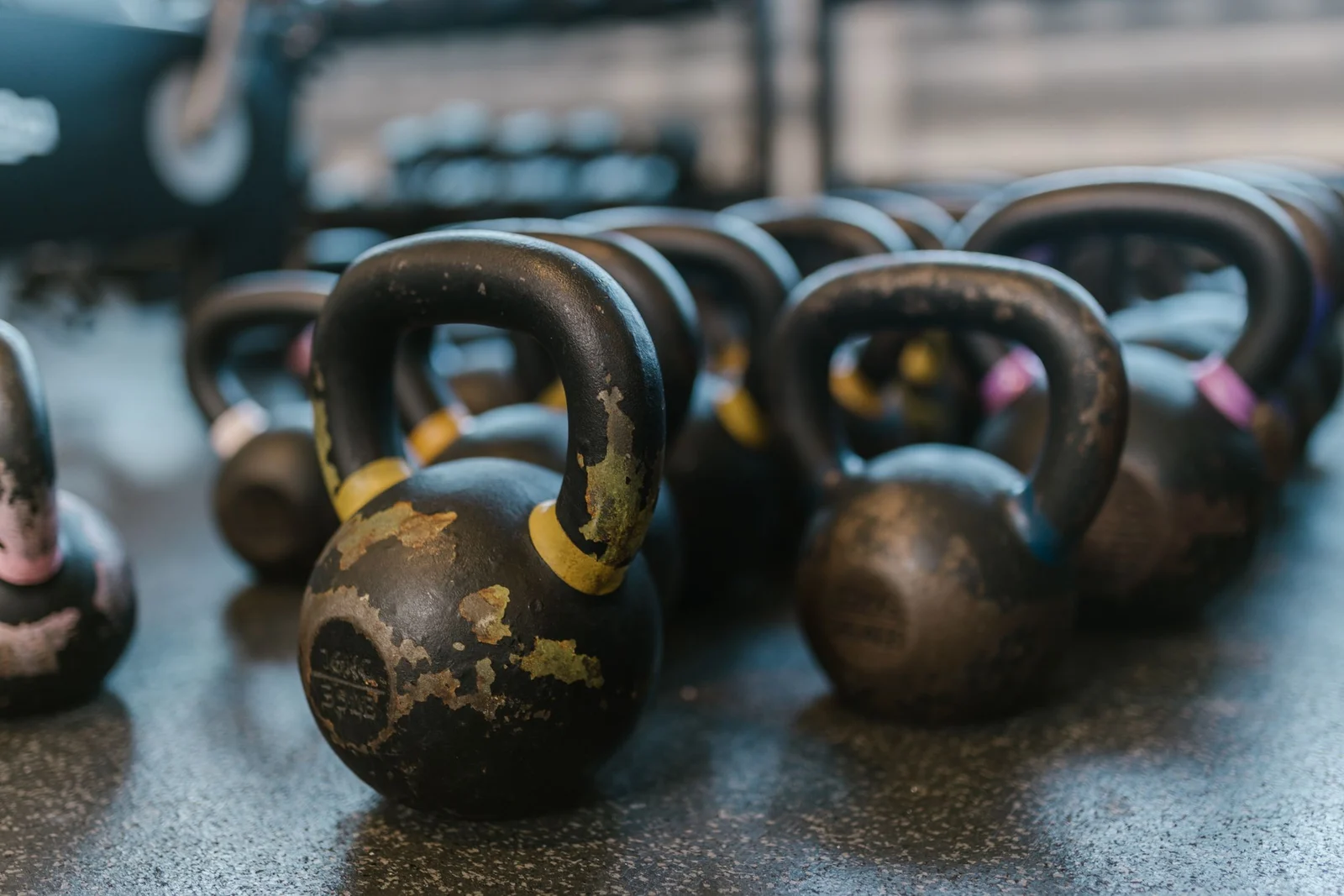 Rows of well-used kettlebells on a rubber floor