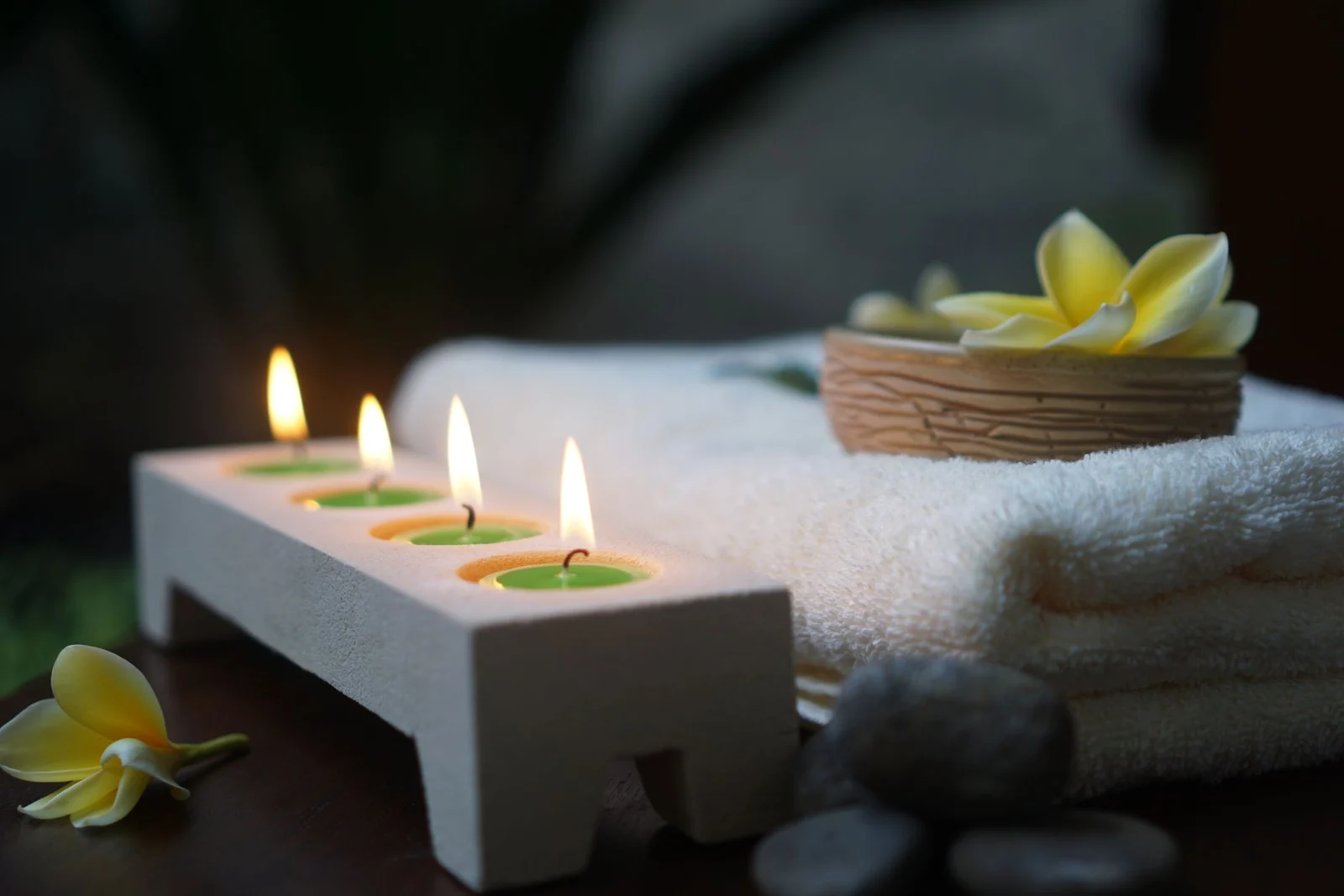 Candles, a folded white towel and frangipani flowers