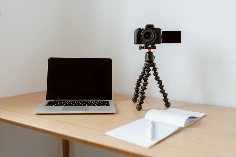 A camera on a tripod beside a laptop