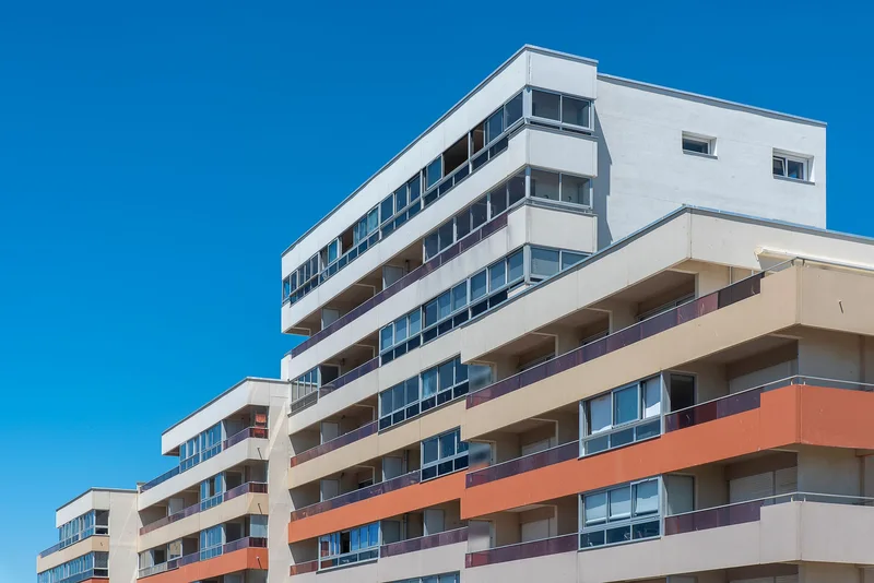 A white and terracotta apartment block under blue sky