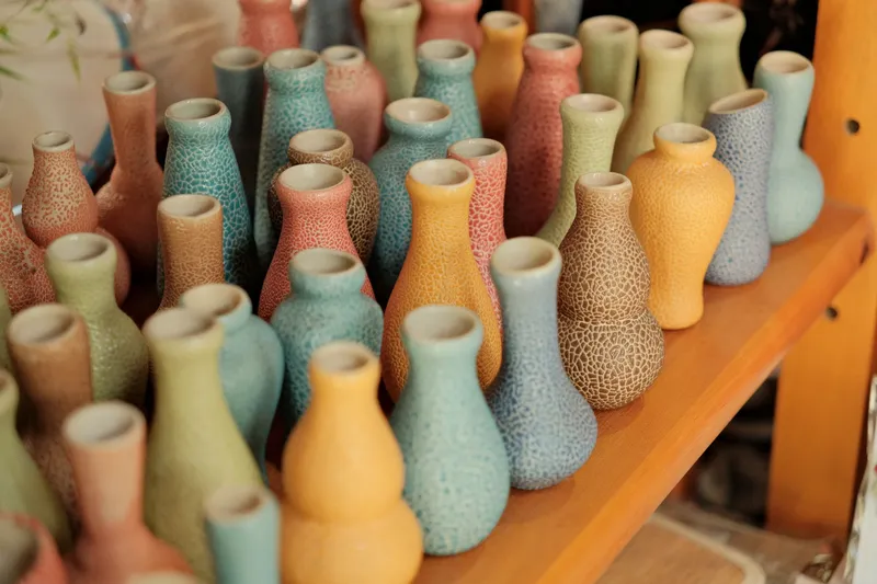 Rows of colourful ceramic vases on a wooden shelf